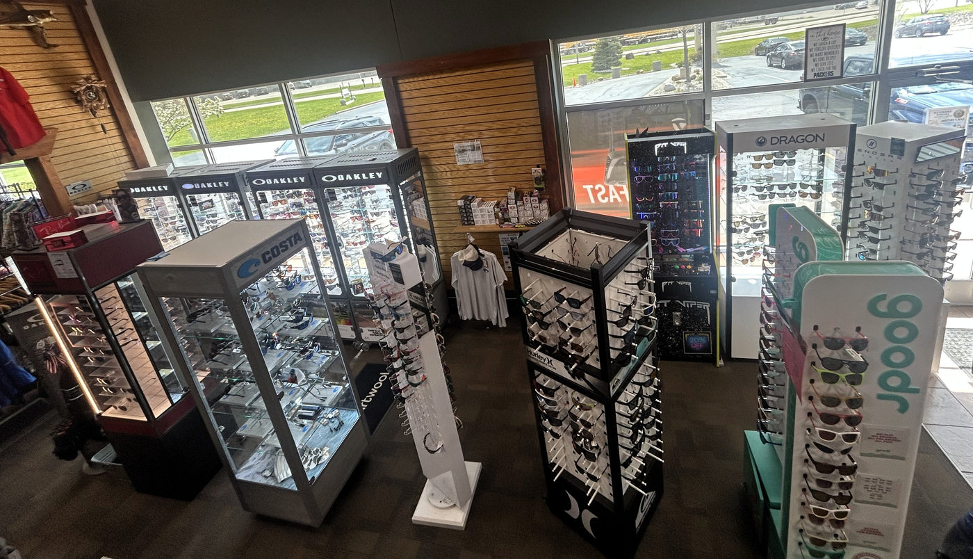 Premium sunglasses selection including Oakley and Ray-Ban at an outdoor sports and golf retailer in Oshkosh, Wisconsin.