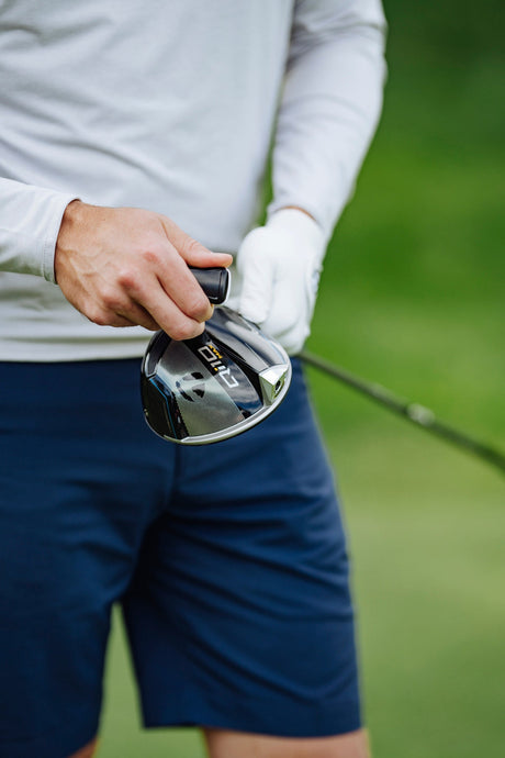 Golfer adjusting a driver head, highlighting its adjustable features for optimizing launch, spin, and overall performance.