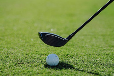 Fairway wood at address beside a golf ball, highlighting its compact head shape, turf‑interaction design, and performance.
