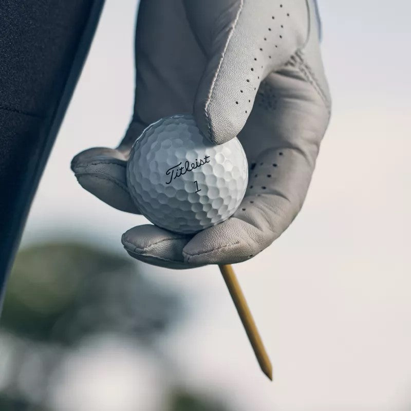 A golfer holding a Titleist Pro V1, illustrating how to choose the right premium golf ball for spin and distance control.