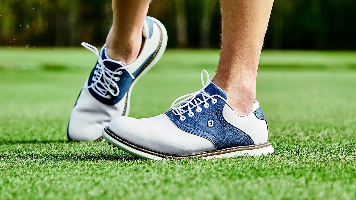 FootJoy saddle-style golf shoes on green grass, featuring a classic leather design and performance traction for stability.