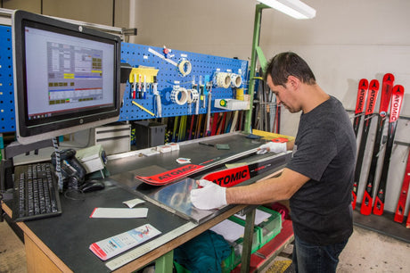 A technician assembling Atomic skis, highlighting the precision engineering and high-quality materials in ski construction.