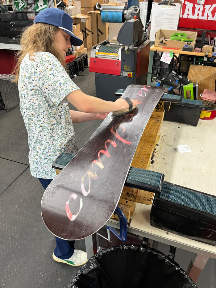 A Ski and Snowboard Service Manager tuning a snowboard base at Golfer's & Skier's Outlet in Oshkosh, Wisconsin.